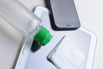 smartphone and tablet on a white background in the place with a bottle of gel sanitizer and napkin. antiviral and antibacterial treatment of wearable gadgets.