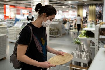 Masked young lady looking at decorative products for her workplace and desk.