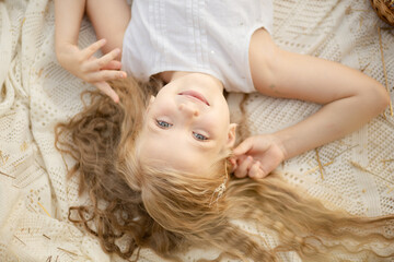 Cute little girl with blond hair on the field with haystacks