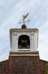 A bell tower of a church with a weather vane above it