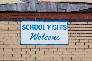 Obraz premium A sign on the exterior of a building that reads school visits welcome
