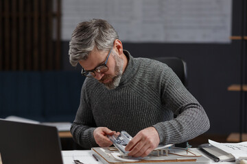 3d architect working in office with building 3D model. Engineer inspect building layout, searching new ideas for construction project. Handsome bearded man at workplace. Business construction concept.