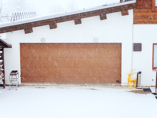 View of the closed garage in the yard during a snowfall