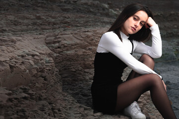 Girl posing with a black and white dress at a rocky cove of the basque coast.