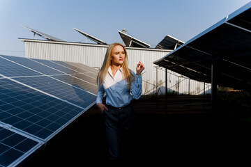 Girl walks between 2 Solar panels row on the ground at sunset. Woman investor wears formal white shirt. Free electricity for home. Sustainability of planet. Green energy.