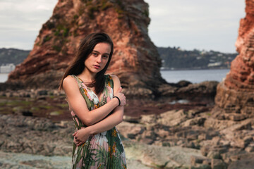 Young girl with a colorful dress posing at a rocky cove at the basque coast.