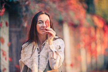 Fall concept - beautiful woman in autumn park under fall foliage