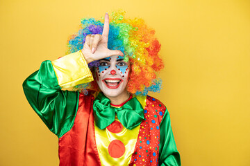 Clown standing over yellow insolated yellow background making fun of people with fingers on...