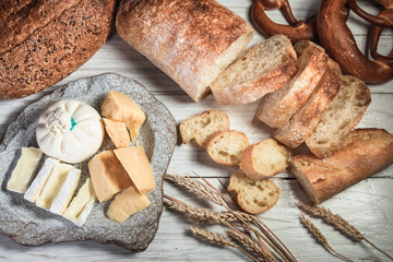 Sliced rustic bread and cheese on a white wooden board. Healthy food and farming concept