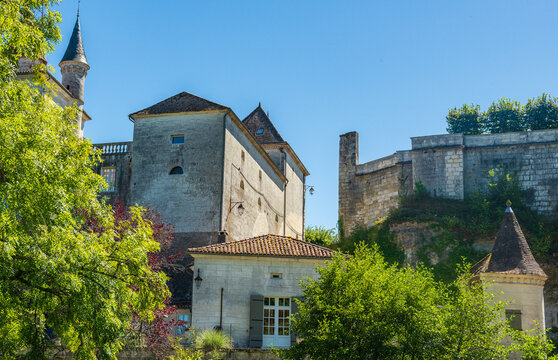 Vue du château de Bourdeilles depuis la rivière avec  des arbres au premier plan avec un ciel bleu totalement dégagé