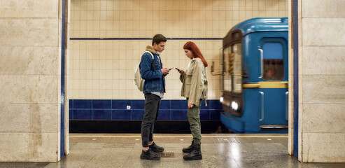 Full length shot of couple of teenagers using smartphones, totally absorbed in online life,...