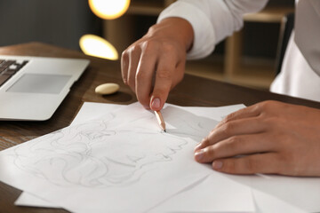 Naklejka premium Man drawing portrait with pencil on sheet of paper at wooden table, closeup