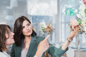 Beautiful women, girls florists in stylish suits in restaurant looking at floral composition....