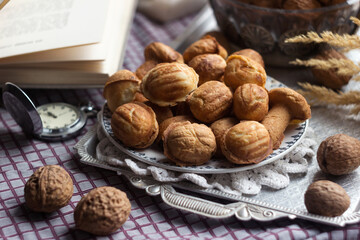 Cookies in the form of walnuts on a metal tray on a checkered tablecloth, next to them are real...