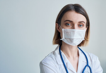 Woman doctor in a medical mask with a stethoscope around her neck