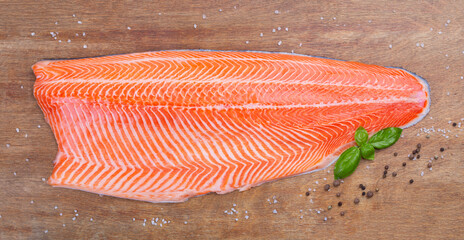 Half raw salmon and basil on  wooden table, top view