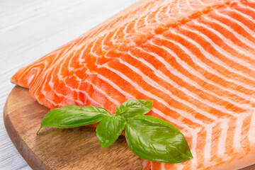 Half raw salmon and basil on white wooden table