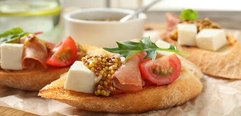 Delicious bruschettas with prosciutto and cheese served on board, closeup. Banner design