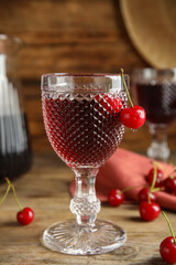 Delicious cherry wine with ripe juicy berries on wooden table