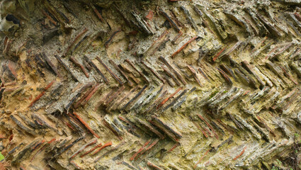 A background of old historic patterned wall, made up of tiles and cement with a herringbone pattern
