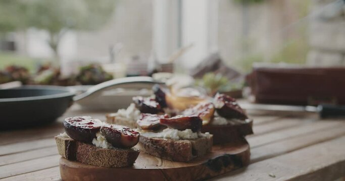 Cook chef fries delicious and healthy snack of fig slices and raw bread with a burner on a wooden table at the summer kitchen.Cooking at home, food or cook blog concept.Closeup