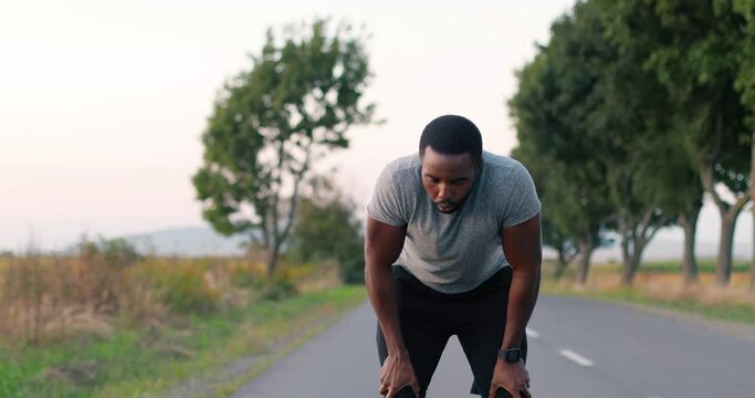 Young African American tired sweaty man jogger stop in running and breathing difficult on road in countryside. Male runner in sweat loosing breath in jogging.