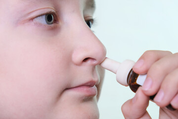 A boy with a runny nose holds a medicine in her hand, nasal spray irrigations to stop allergic...