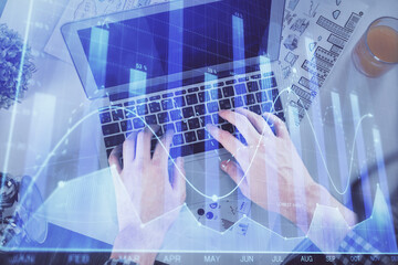 Plakat Double exposure of man's hands typing over laptop keyboard and forex chart hologram drawing. Top view. Financial markets concept.