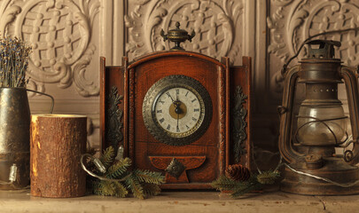the antique clock on the mantelpiece shows five minutes to midnight. Close-up in a low key, with vintage interior items. The concept of the new year