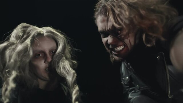 Close up portrait of two scary zombie on dark background.