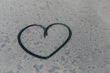Heart symbol on dirty car window. Heart drawn with a finger on the glare side window of a car....