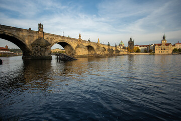 
the monument of Charles Bridge from 1402 and the level of the flowing Vltava river and the light from the sun at sunset in the center of Prague in the Czech Republic