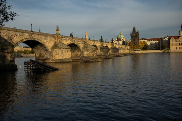 Obraz premium the monument of Charles Bridge from 1402 and the level of the flowing Vltava river and the light from the sun at sunset in the center of Prague in the Czech Republic