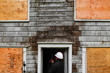 Cornwall, Ct, USA  An insurance fire inspector inspects the exterior  of a wooden house damaged by...