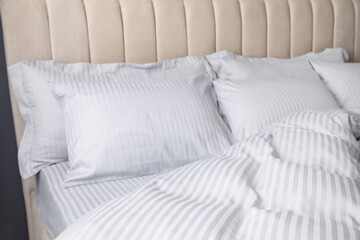 Comfortable bed with soft blanket and pillows, closeup