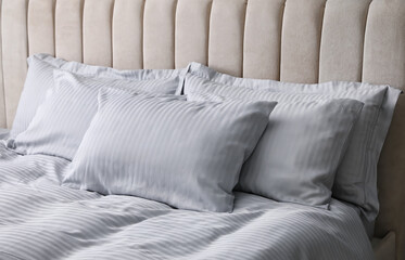 Comfortable bed with soft blanket and pillows, closeup