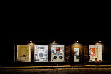Canaan, Connecticut USA  A single man sits inside of a laundromat at night.