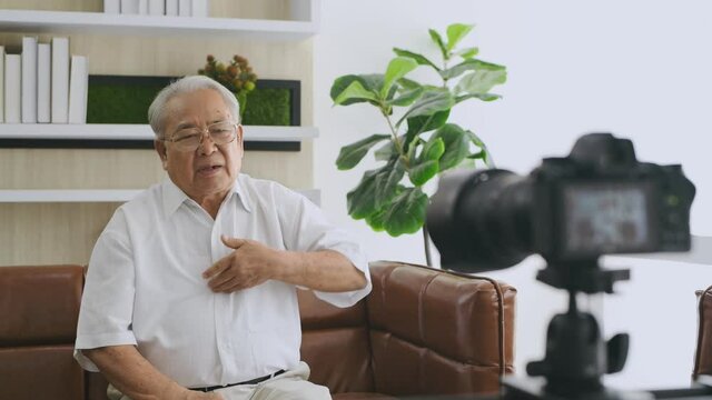 Family concept. An elderly Asian man is giving an interview about his health in the living room. 4k Resolution.