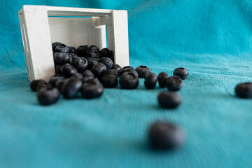 Fresh blueberries in wooden box on turquoise background