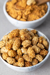 Mulberry Fruit Powder. A bowl of white dried mulberry  and dried mulberry powder on stone background.
