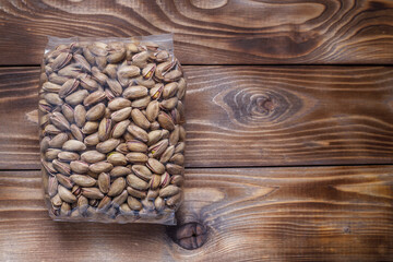 Plastic bag with pistachios on a wooden background. Flat layout