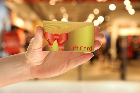 Woman holding gift card in shopping mall, closeup