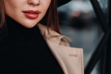 Fototapeta na wymiar Close-up of the lips of a girl in a beige coat. Women's street fashion. Autumn clothing.