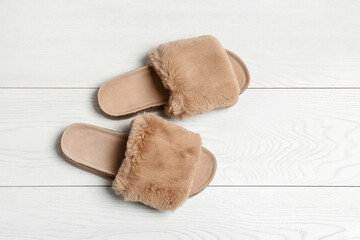 Pair of soft slippers on white wooden background, flat lay