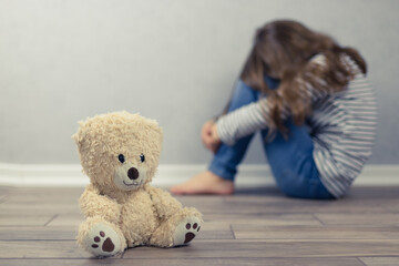 Psychological health concept. A teddy bear and in the background a teenage girl out of focus....