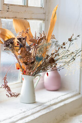 Arrangement of dried flowers in a white ceramic vase.