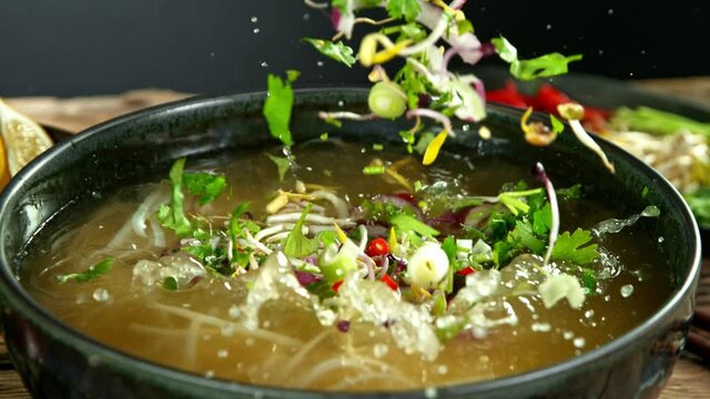 Super Slow Motion Detail Shot of Ingredients Falling into Vegetable Pho Soup at 1000 fps.