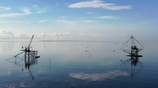 4K drone footage of pakpra fisherman village and traditional fishing net made by bamboo in sea with tourism boat sightseeing in morning located in Phatthalung province Thailand