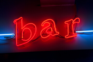 Red neon bar sign with blue neon lines on the sides, lower case letter lights. Concept of night life in city and place to relax after a hard week of work in the city.