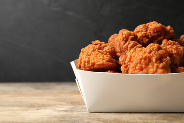 Tasty deep fried chicken pieces on wooden table, closeup. Space for text